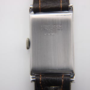 Close-up of the polished stainless steel case back with "FOND ACIER INOXYDABLE" and serial number 3802 engraving.