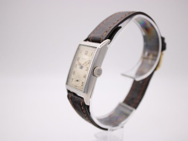 Right-side view of the PRONTO watch showing the crown, rectangular silver case, and strap.