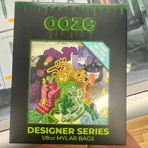 May include: Black box with the word "ooze" in green dripping letters. The box features a colorful cartoon illustration and text that reads "Designer Series 1/8oz Mylar Bags." The box also states "10 Count Smell Proof Child Resistant."