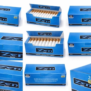 May include: Blue boxes of "ZED" white cigarette tubes, with the text "WHITE CIGARETTE TUBES" and "250 TUBES". Some boxes are open, revealing the cigarettes. The boxes have a black and white logo.