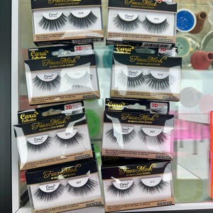 May include: Multiple boxes of Cara Faux Mink 3D multi-layer effect eyelashes are displayed. Each box features a pair of false eyelashes, with varying styles and lengths. The packaging includes the brand name and product numbers.