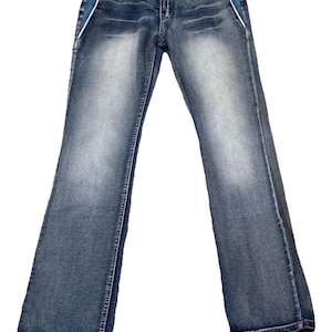 May include: Blue denim jeans with a faded wash. Features include decorative patches, white side stripes, and a flared leg. The jeans have a classic five-pocket design and a button and zipper closure.