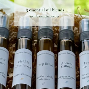 May include: Five 10 mL sample bottles of essential oil blends. Each bottle has a white label with the name of the blend and ingredients. The blends include Emotional Sanctuary, Held & Comforted, Deep Exhale, Ancient Stillness, and First Breath.