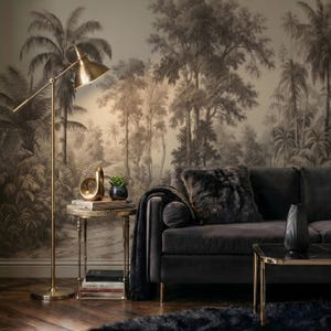 May include: A stylish living room with a dark grey sofa, a faux fur cushion, and a black throw. A gold floor lamp lights a side table with decor. The backdrop is a sepia-toned jungle mural, creating a sophisticated atmosphere.