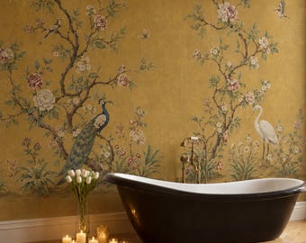 May include: A black freestanding bathtub sits against a mustard yellow wall featuring a mural of flowering branches, a peacock, and a white heron. A glass vase with white tulips and several lit candles are placed on the floor nearby.