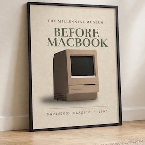 Puede incluir: Un póster enmarcado con una ilustración de un ordenador Macintosh Classic beige sobre un fondo crema. El texto dice THE MILLENNIAL MUSEUM, BEFORE MACBOOK y MACINTOSH CLASSIC 1990. El marco es fino y negro, rodeando la impresión.