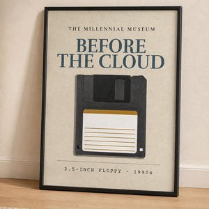 May include: A framed wall art print featuring a black 3.5-inch floppy disk centred on a beige background. The text reads THE MILLENNIAL MUSEUM, BEFORE THE CLOUD, and 3.5-INCH FLOPPY 1990s. The print is enclosed in a thin black frame with a clean aesthetic.