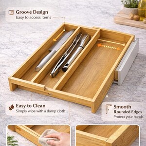 Może przedstawiać: Bambusowy organizer do szuflady z trzema przegrodami, mieszczący n&oacute;ż i przybory do serwowania. U g&oacute;ry tekst "Thoughtful Design Details". Zawiera "Groove Design", "Easy to Clean" i "Smooth Rounded Edges".
