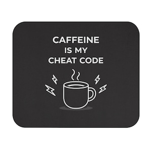 May include: Black mousepad with a white graphic of a coffee mug emitting steam, surrounded by lightning bolts. The text "CAFFEINE IS MY CHEAT CODE" is above the mug. The mousepad has rounded corners.