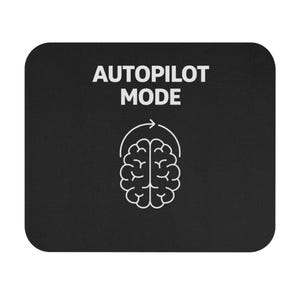 May include: Black mouse mat with rounded corners. The text "AUTOPILOT MODE" is in white, above a white brain graphic with a curved arrow. The mouse mat is a solid black colour.