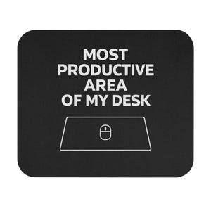 Op de afbeelding: Zwart rechthoekig muismatje met afgeronde hoeken. Het muismatje heeft witte tekst met de tekst "MOST PRODUCTIVE AREA OF MY DESK". Een witte omtrek van een muis en muismatje staat eronder.