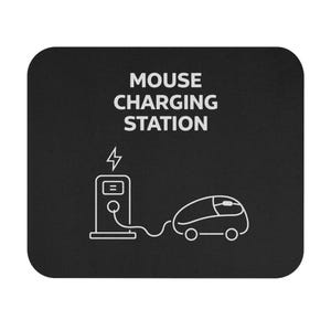 Op de afbeelding: Zwarte muismat met witte afbeelding van een laadstation en een computermuis. De tekst "MOUSE CHARGING STATION" staat bovenaan. De muis is via een kabel verbonden met het laadstation.