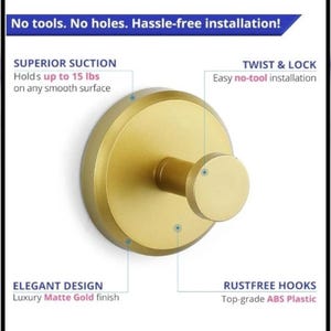 May include: A gold-colored wall hook with a matte finish. The hook is round with a circular base and a cylindrical hook extending from the center. Text on the image reads "No tools. No holes. Hassle-free installation!" and "Holds up to 15 lbs".