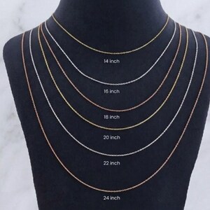 May include: A display of six delicate chain necklaces in gold, silver, and rose gold tones, each with a different length. The lengths are labeled: 35.5 cm, 40.6 cm, 45.7 cm, 50.8 cm, 55.9 cm, and 61 cm.