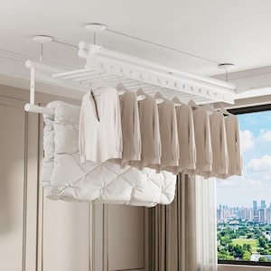 May include: A white ceiling-mounted clothes airer with multiple hangers holding light-coloured shirts. A large, white, quilted duvet is also hanging. The airer is suspended from the ceiling with a view of a city skyline through a window.