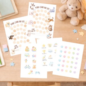 Op de afbeelding: Kinderbeloningskaarten en stickers met schattige dierenillustraties. De kaarten hebben de tekst "YOU CAN DO IT!" en stippen om de voortgang bij te houden. Extra stickers bevatten pootafdrukken en motiverende iconen.