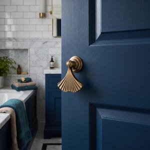 May include: A brass door handle with a fan-shaped, ribbed design mounted on a dark navy blue painted wooden door. The handle features a curved neck and a wide, textured base that flares outward, providing a metallic contrast to the door.