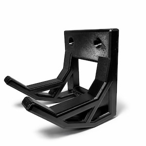 May include: A black wall-mounted hanger featuring two parallel, angled support arms extending from a rectangular base plate. The structure is constructed with a rigid, geometric frame and includes two circular mounting holes on the back plate.