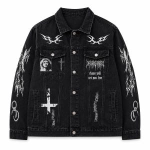 May include: A black denim jacket featuring white graphic prints, including tribal patterns on the chest and sleeves, a portrait, a cross, and the text "chaos will set you free". The jacket has a button-up front, two chest pockets, and long sleeves.