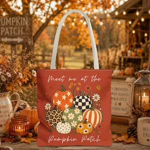 May include: A rust-colored tote bag with white handles featuring a graphic of various pumpkins with patterns including stars, leopard print, and checkers. The text reads Meet me at the Pumpkin Patch in white script lettering surrounded by small flowers.