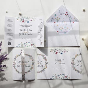 May include: A wedding invitation suite with floral designs and the names "Gloria and William." The suite includes an invitation, RSVP card, and envelope. The invitation is white with colorful floral accents.