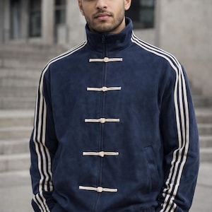May include: Navy blue track jacket with cream-colored stripes on the sleeves and a high collar. The jacket features a zip closure and unique toggle closures down the front. A stylish and comfortable athletic jacket.
