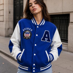 Female model styling premium blue varsity bomber jacket with white sleeves and street fashion look”