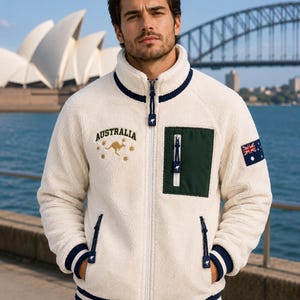 Australia Sherpa Fleece Jacket for Men in cream white teddy fleece with forest green chest pocket, navy ribbed collar and cuffs, Australian flag sleeve patch, kangaroo embroidery, Sydney Opera House background.