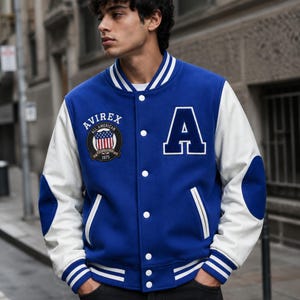 Men model styling premium blue varsity bomber jacket with white sleeves and street fashion look”