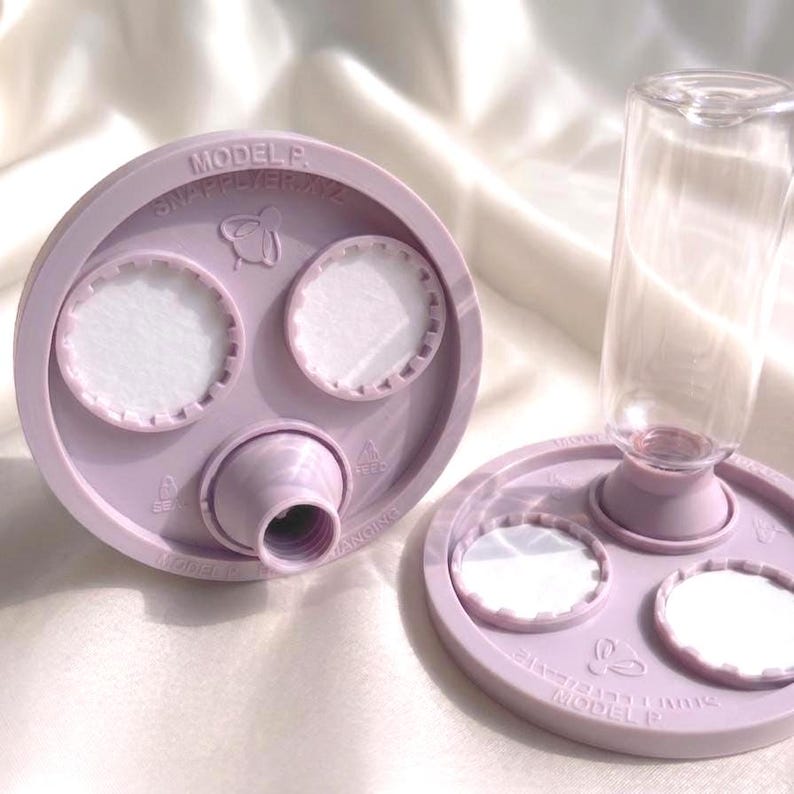 Peut inclure: Deux bases circulaires en plastique violet clair avec des inserts circulaires blancs et une ouverture centrale filet&eacute;e. Une base est fix&eacute;e &agrave; une bouteille en plastique transparent. Chaque base porte le texte MODEL P et SNAPPLYER.XYZ avec une ic&ocirc;ne d'abeille.