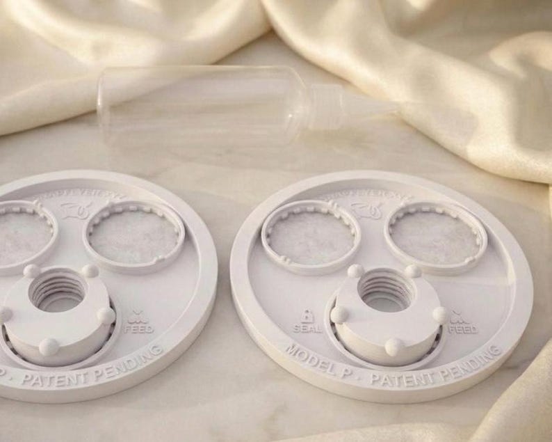 Peut inclure: Deux couvercles circulaires en plastique blanc avec des centres filet&eacute;s et deux petites ouvertures circulaires, pr&eacute;sentant un texte en relief indiquant MODEL P, PATENT PENDING, SEAL et FEED, avec un flacon souple transparent.