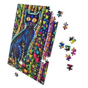 May include: A colorful jigsaw puzzle featuring a black cat with yellow eyes, set against a vibrant floral background. The puzzle is partially assembled, with several pieces scattered nearby. The artwork has a whimsical, artistic style.