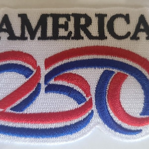 May include: Embroidered patch with the word "AMERICA" in black above the number "250" in red and blue. The patch has a white background and a decorative border.