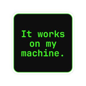 May include: A square sticker with rounded corners featuring a black background and a bright neon green border. The text "It works on my machine." is printed in the center in a matching neon green, monospaced, sans-serif font style.