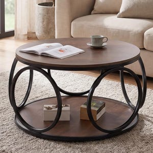 May include: A round coffee table with a dark brown wooden top and a lower shelf. The table has a black metal frame with a unique circular design. A book and a teacup sit on top.