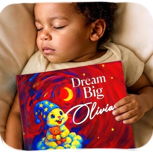 Può includere: Un libro con copertina rigida intitolato Dream Big Olivia con uno sfondo rosso vivace, una luna crescente gialla e stelle. L'illustrazione di copertina raffigura un coniglio giallo con un berretto da notte blu stellato che tiene un orsacchiotto.