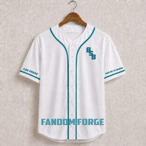 Puede incluir: Una camiseta de béisbol blanca con ribetes y botones de color verde azulado. El frente presenta el texto BSB, LAS VEGAS, TAKE ME TO CHURCH y FANDOM FORGE en letras verde azulado. La camiseta tiene mangas cortas y está en una percha.