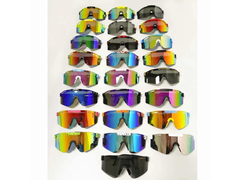 May include: A collection of colorful sports sunglasses with mirrored lenses. The sunglasses come in various colors, including yellow, green, blue, red, and black. The lenses have a reflective, iridescent finish. The frames are made of plastic.