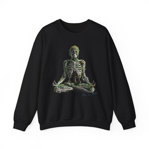 Peut inclure: Sweat-shirt noir avec une illustration détaillée d'un squelette en position méditative, orné de feuillage vert. Le design comprend le texte "Zen as Hell". Un vêtement confortable et décontracté.