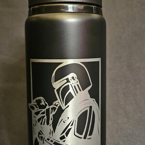 May include: Black water bottle with a flip-top lid. The bottle features a silver graphic of a character from a popular science fiction series, holding a small creature. The text "STILL WEDNESDAY" is below the graphic.