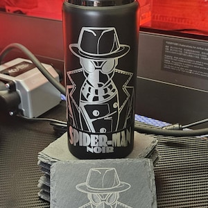 Peut inclure: Une bouteille d'eau en m&eacute;tal noir avec un bouchon &agrave; vis noir, pr&eacute;sentant une gravure laser du personnage Spider-Man Noir et le texte "SPIDER-MAN NOIR" en blanc, accompagn&eacute;e d'un dessous de verre carr&eacute; en ardoise avec le m&ecirc;me motif grav&eacute;.