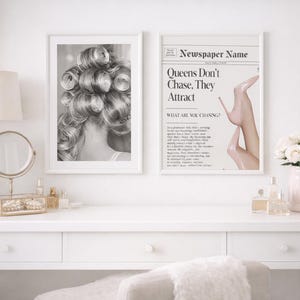 May include: Two framed prints on a white vanity. One is a black and white image of a woman's hair in rollers. The other is a newspaper-style print with the text "Queens Don't Chase. They Attract."