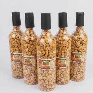 May include: Five clear bottles filled with roasted peanuts, each topped with a black cap. The bottles have labels that read "Roasted Peanut". The peanuts are a light brown color and fill the bottles completely.