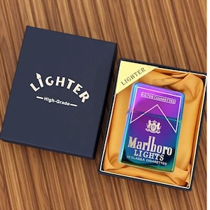 May include: An iridescent Marlboro Lights lighter in a navy gift box. The box is labelled "Lighter - High-Grade-". The lighter is displayed in a black box with gold satin lining. The lighter has a metallic finish.