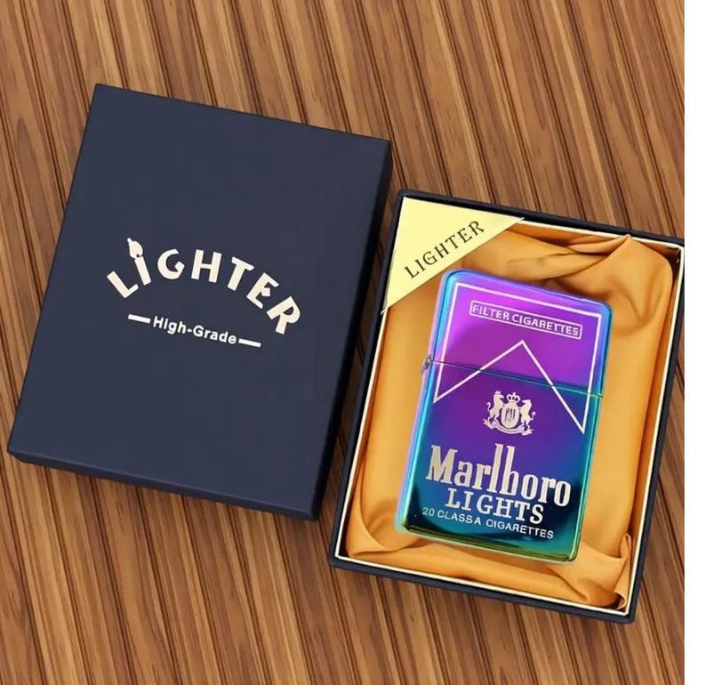 May include: An iridescent Marlboro Lights lighter in a navy gift box. The box is labelled "Lighter - High-Grade-". The lighter is displayed in a black box with gold satin lining. The lighter has a metallic finish.