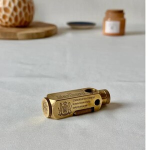 May include: A brass-colored, rectangular lighter with the word "Marlboro" engraved on the top. The lighter has a textured end and a small switch. The text "LED lights..." is also visible. A decorative crest is on the side.