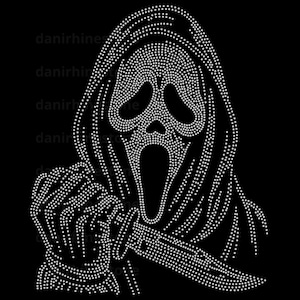 May include: A rhinestone transfer design on a black background featuring a hooded figure with a mask, large hollow eyes, and an open mouth. The figure holds a knife in one hand. The design is composed of small white dots forming the image.