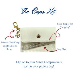 May include: The Oops Kit is a white pouch with a clear front window containing a seam ripper and a snag tool. It features a gold lobster claw clasp with a shamrock charm. Text includes The Oops Kit, Seam Ripper for Frogging, Snag Tool, and Clip on to your Stitch Companion or toss in your project bag!