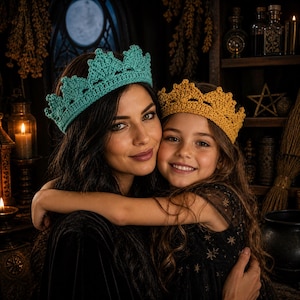 May include: A mother and child wearing crocheted crowns. The woman's crown is teal, and the child's is gold. The crowns have a scalloped design. The background features candles, a shelf with bottles, and a window with a moon.