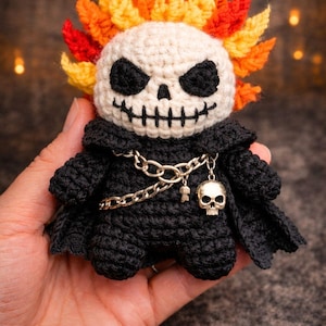 May include: A handmade crochet Flaming Skull Rider doll. The doll features a skull head with flames, a black cloak, and a silver chain with a skull pendant. The text "The Christmas Witch shop" and "Flaming Skull Rider" are visible.